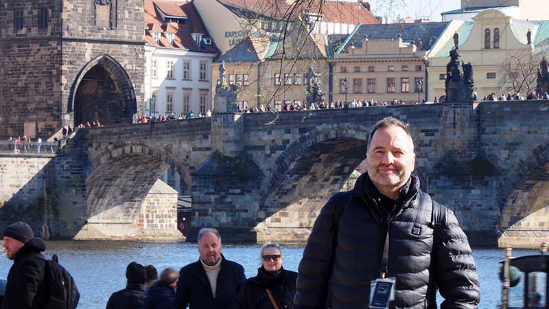 Mateo, guía oficial de Praga, sonriendo a cámara con su acreditación profesional visible durante un tour de día.