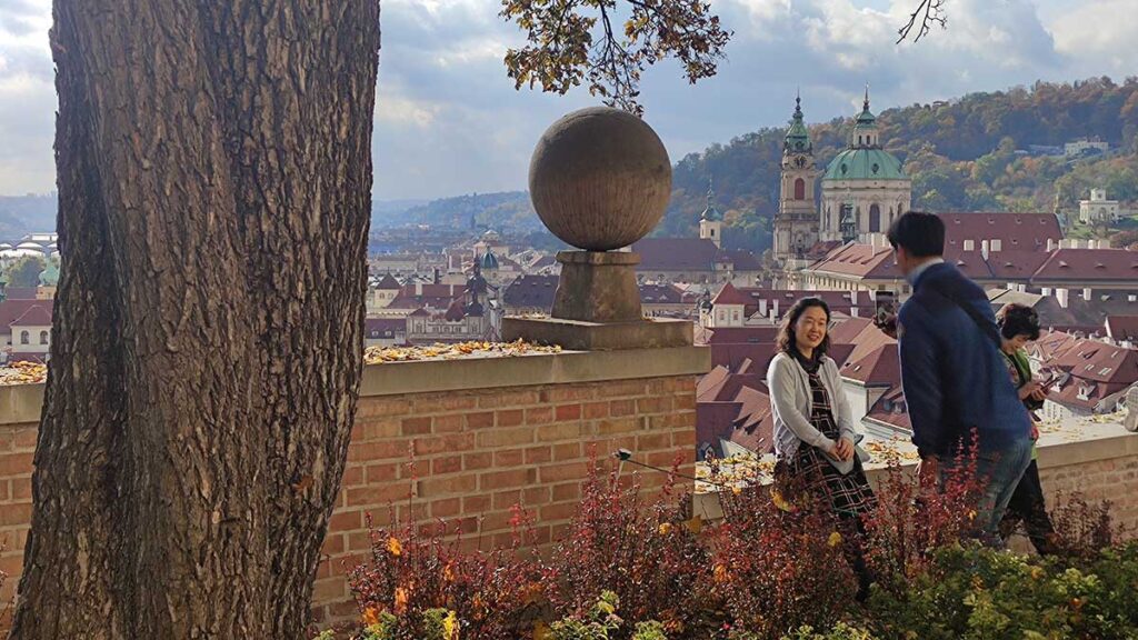 Turistas posando en un mirador del Castillo de Praga con vistas a Malá Strana y la cúpula de San Nicolás.