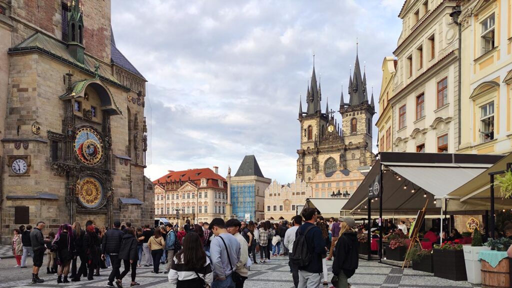 Vista de la torre del Reloj Astronómico de Praga con la Iglesia de Týn al fondo durante el atardecer.