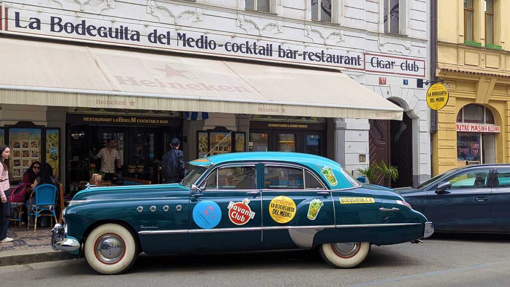Coche clásico americano turquesa aparcado frente al bar La Bodeguita del Medio en la calle Kaprova, un punto clave de la vida nocturna en Praga.