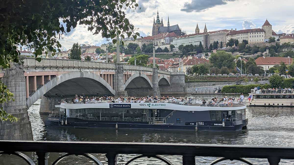Paseo en barco por el río Moldava en Praga Barco turístico navegando por el río Moldava frente al Puente de Carlos en Praga durante el atardecer.